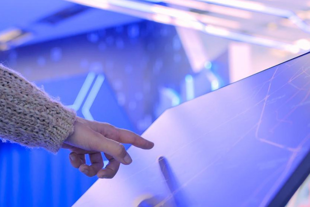 A woman’s hand interacting with an interactive retail display board.